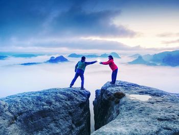 Hikers or climbers on mountain. couple hold light high above danger gulch between rocks. night photo