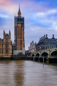 Buildings by river against sky