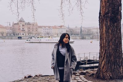 Young woman standing by lake against sky during winter