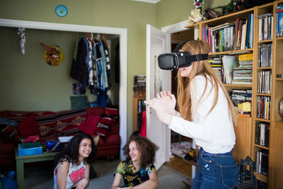 Blond girl wearing virtual reality headset while friends sitting at home