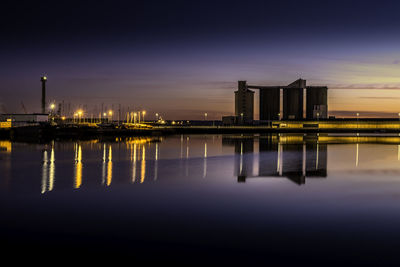 Reflection of illuminated bridge over river at sunset