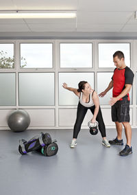 Personal trainer helping client at gym in the uk