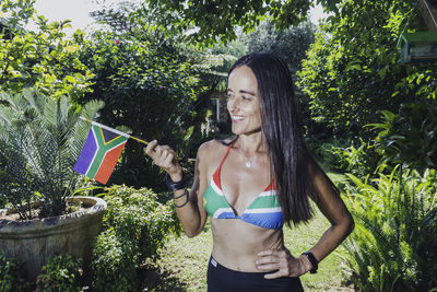 Beautiful woman holding up the south african flag., while wearing a south african bikini. 