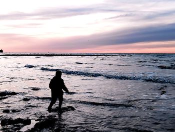 Silhouette man on beach against sky during sunset