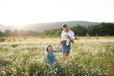 Mother and daughter walking in field