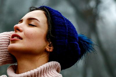 Close-up of young woman with eyes closed standing outdoors during winter