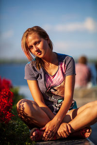 Young woman sitting in sea against sky