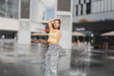 Woman standing by fountain in city 