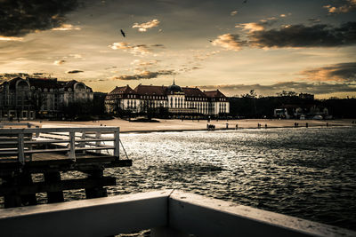 Houses by sea against sky during sunset