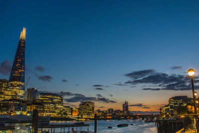 Illuminated buildings against sky at dusk