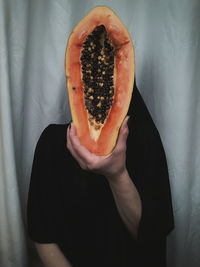 Midsection of man holding papaya