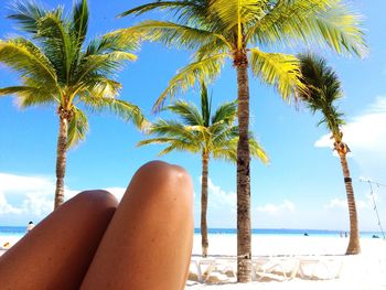 Midsection of woman at beach against blue sky