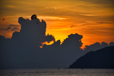 Silhouette man by sea against sky during sunset