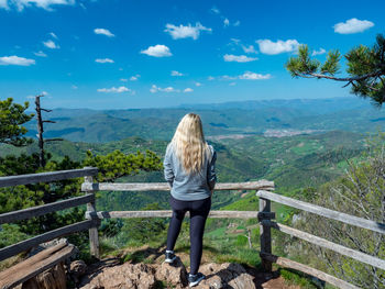 Rear view of woman standing on mountain against sky