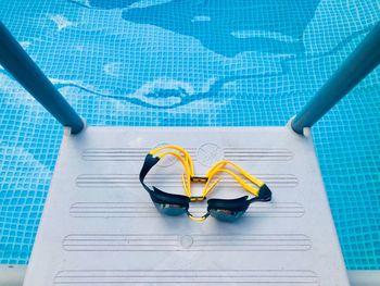 High angle view of goggles on ladder by swimming pool