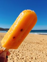 Close-up of hand holding ice cream on beach