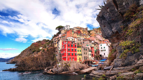 View of buildings by sea against cloudy sky