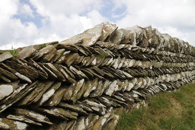 Close-up of stack of firewood on field against sky