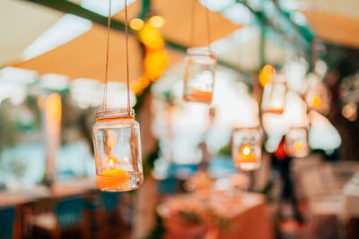 Close-up of illuminated candle in jar hanging