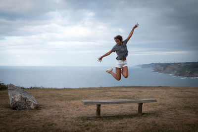 Full length of girl jumping against sea and sky