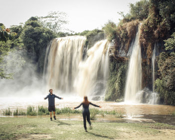 Rear view of man standing against waterfall
