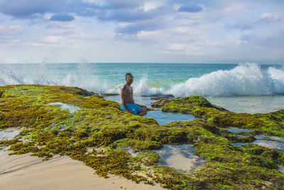 Side view of man standing at beach against sky