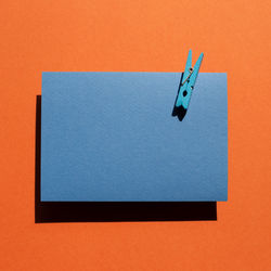 Blue memo pad with wooden clip on red background. top view, copy space