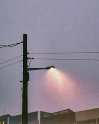 Low angle view of electricity pylon against sky during sunset