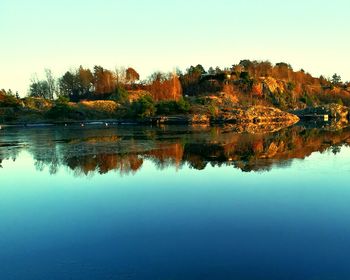 Reflection of trees in lake against clear sky