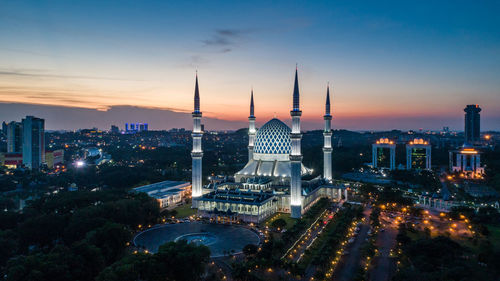 Illuminated buildings in city against sky during sunset