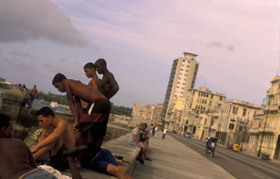 Tilt image of people on shore by street against sky