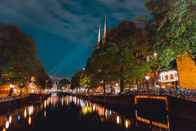 River amidst illuminated buildings against sky at night