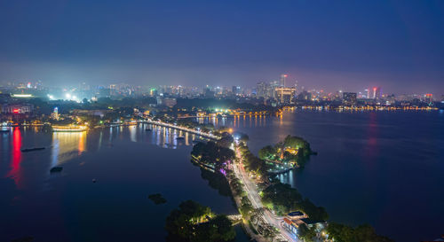 High angle view of illuminated city by river against sky