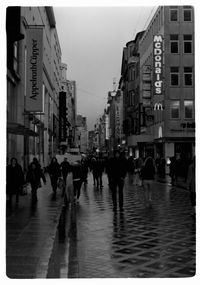 Group of people walking on wet street in city