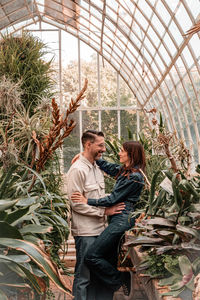 Portrait of young couple standing against plants