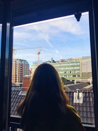 Rear view of woman looking through window