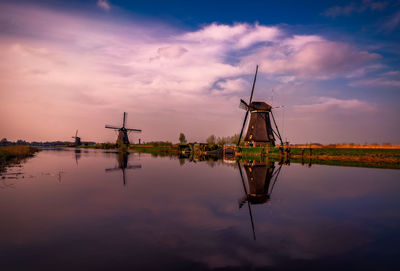 Traditional windmills by lake during sunset