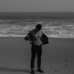 Rear view of shirtless man standing on beach