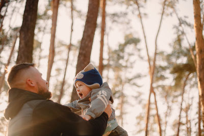 Father playing with son outdoors in park in autumn