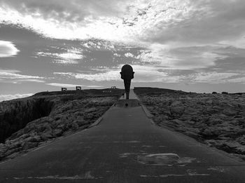 Rear view of woman standing on shore against sky