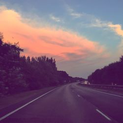 Road amidst trees against sky during sunset