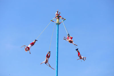 Low angle view of kites flying against clear blue sky