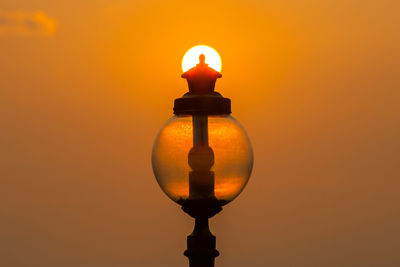 Close-up of illuminated lamp against orange sky