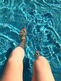 Low section of woman legs in swimming pool