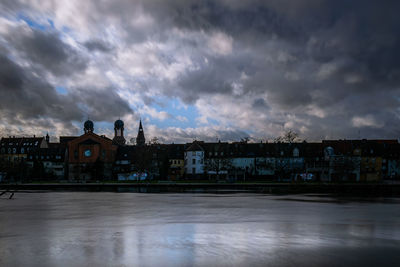 Buildings by river against sky in city