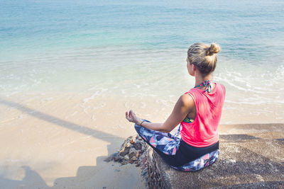 Rear view of woman sitting on beach