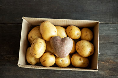 Red potato in the shape of a heart in a cardboard box among white potatoes