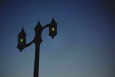 Low angle view of illuminated street light against blue sky
