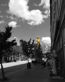 Trees in city against cloudy sky