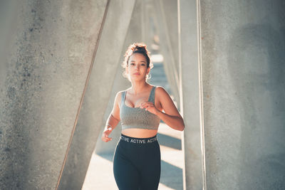 Female athlete running between column